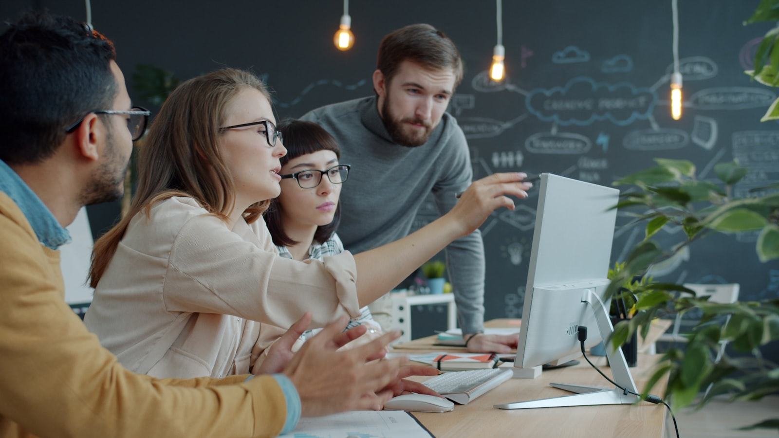 A small team gathered around a laptop in an office