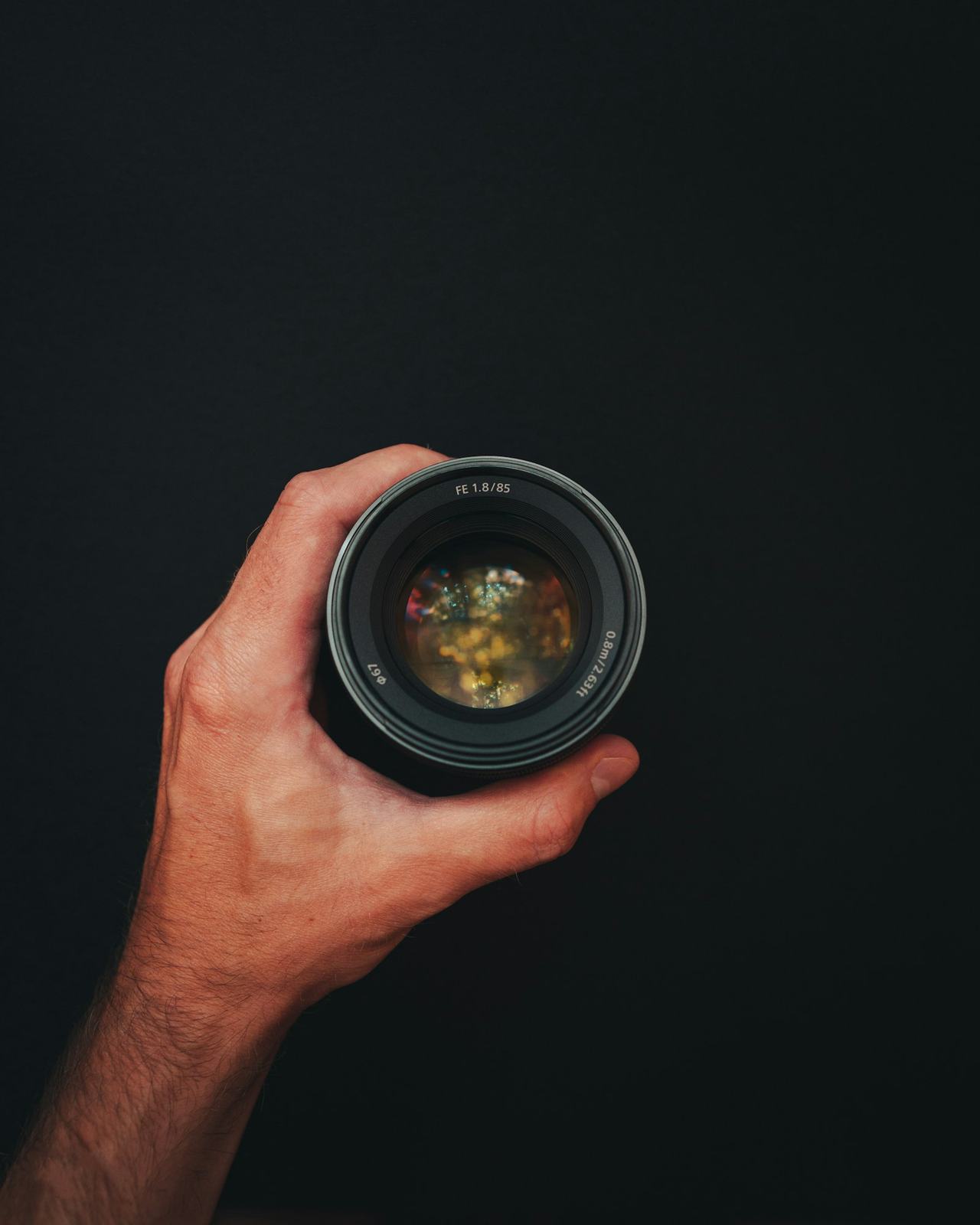 A hand holding a camera against a dark bokeh background