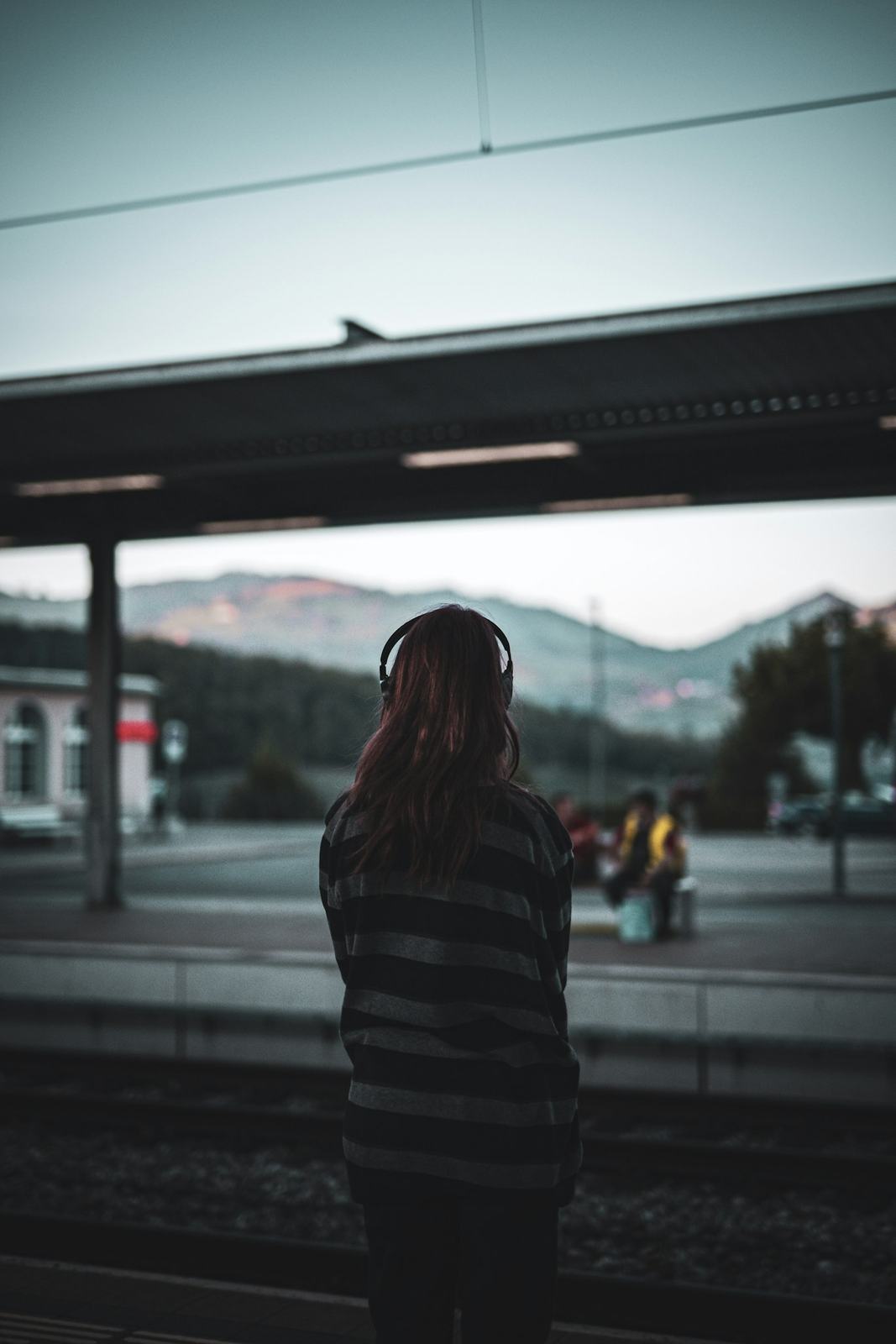 A person wearing headphones on a train platform