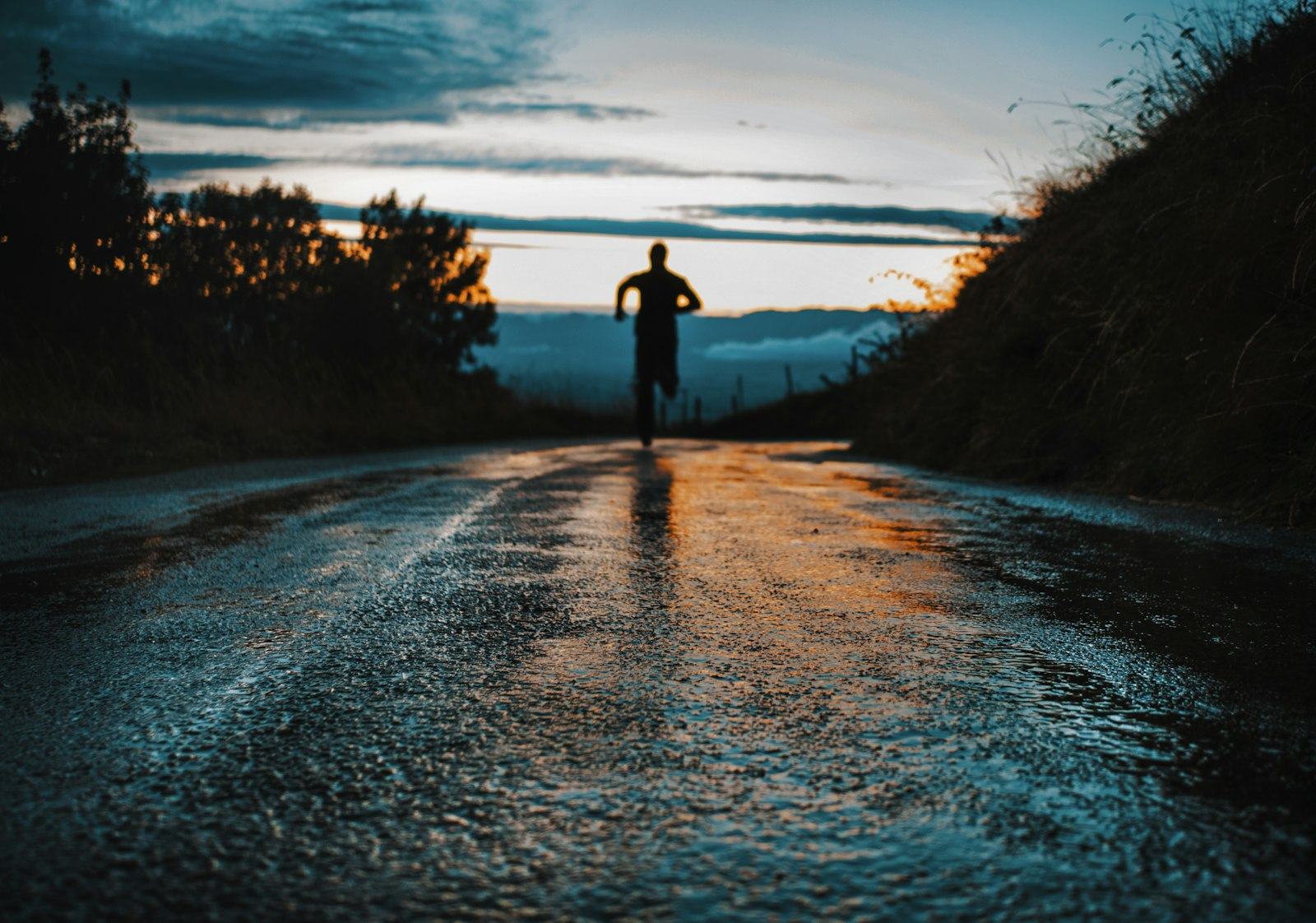 A silhouetted runner on a road at dawn